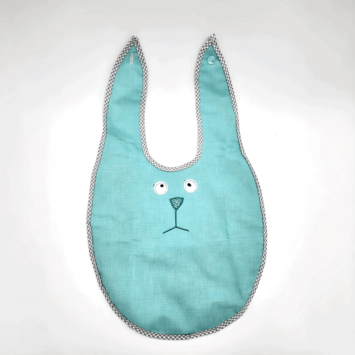 Das Esslätzchen ist ein blaugrünes Babylätzchen mit einem Hasengesichtsdesign und kariertem Rand auf weißem Hintergrund.