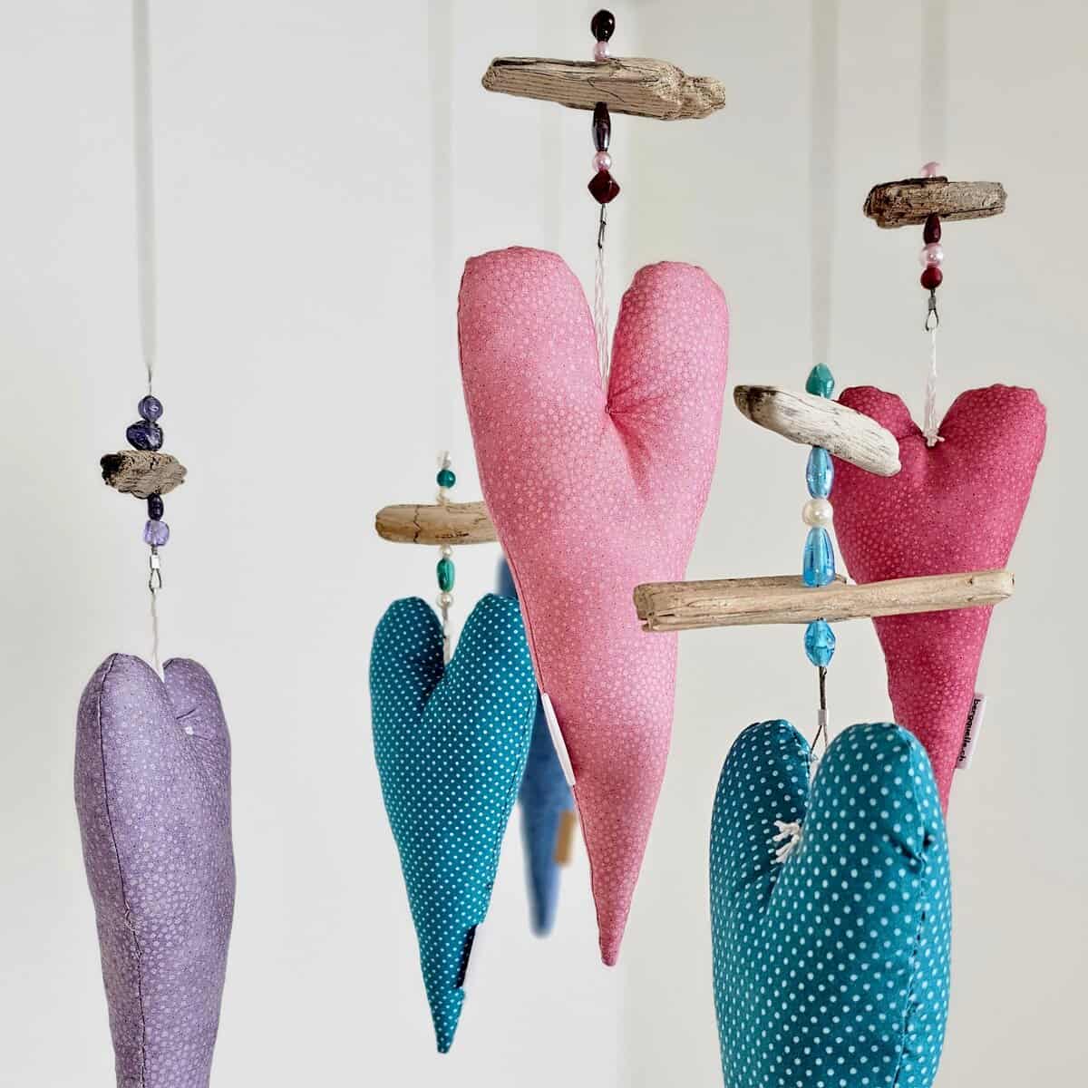 Fotoleine mit Herz bestehend aus einem Mobile mit bunten Stoffherzen und Holzteilen, die an Schnüren aufgehängt sind.