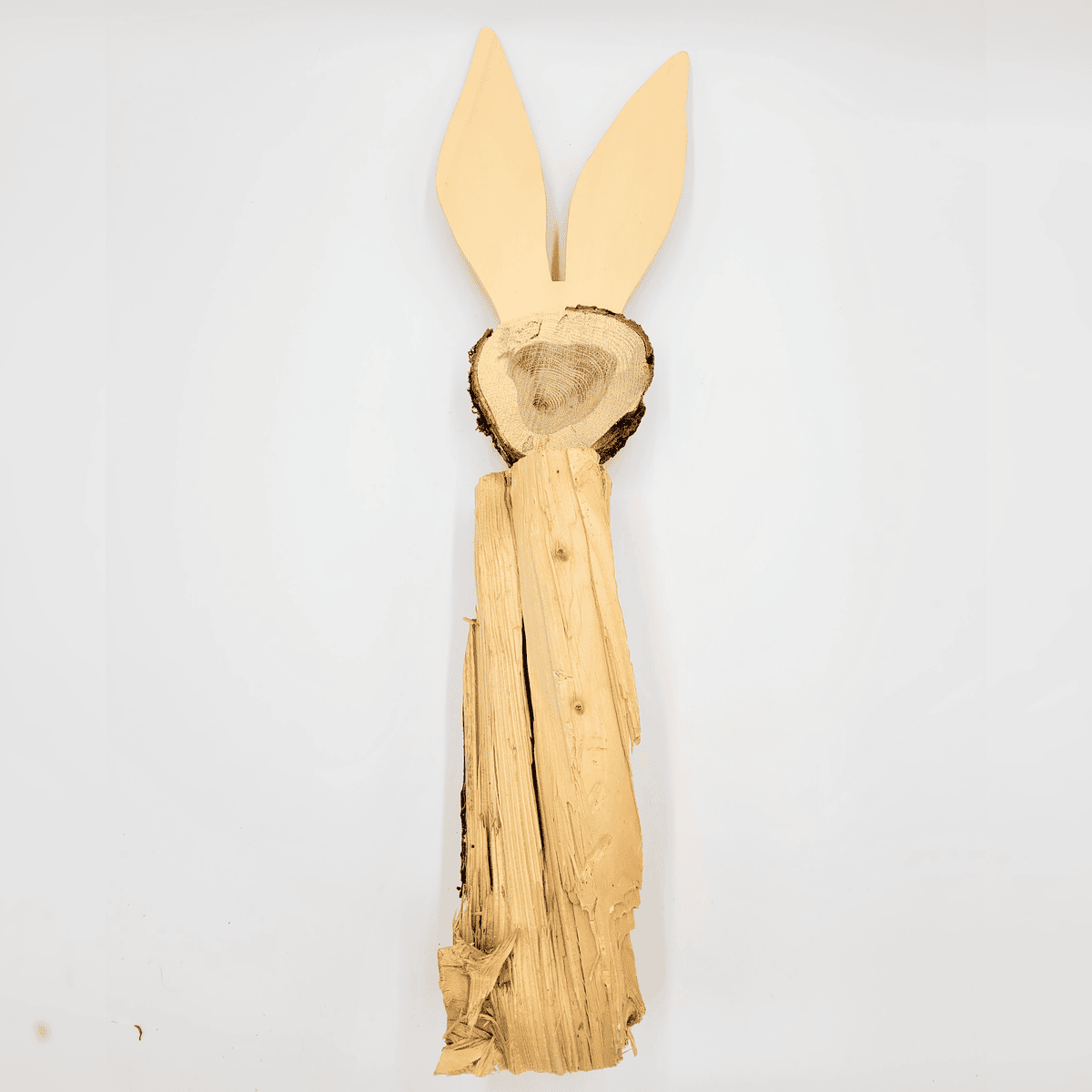 Der Hase ist eine aus Baumrinde und Baumstämmen gefertigte Holzskulptur eines stehenden Kaninchens mit langen Ohren.