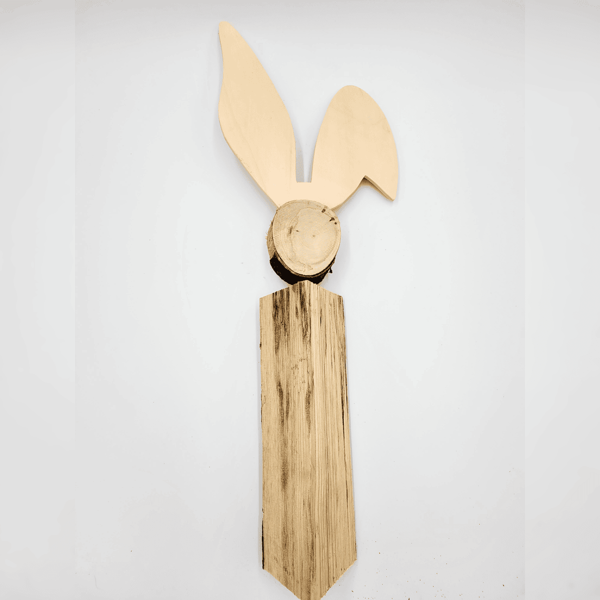 Hase: Ein hölzerner Hasenkopf mit langen Ohren und einem strukturierten, verlängerten Hals vor einem schlichten Hintergrund.