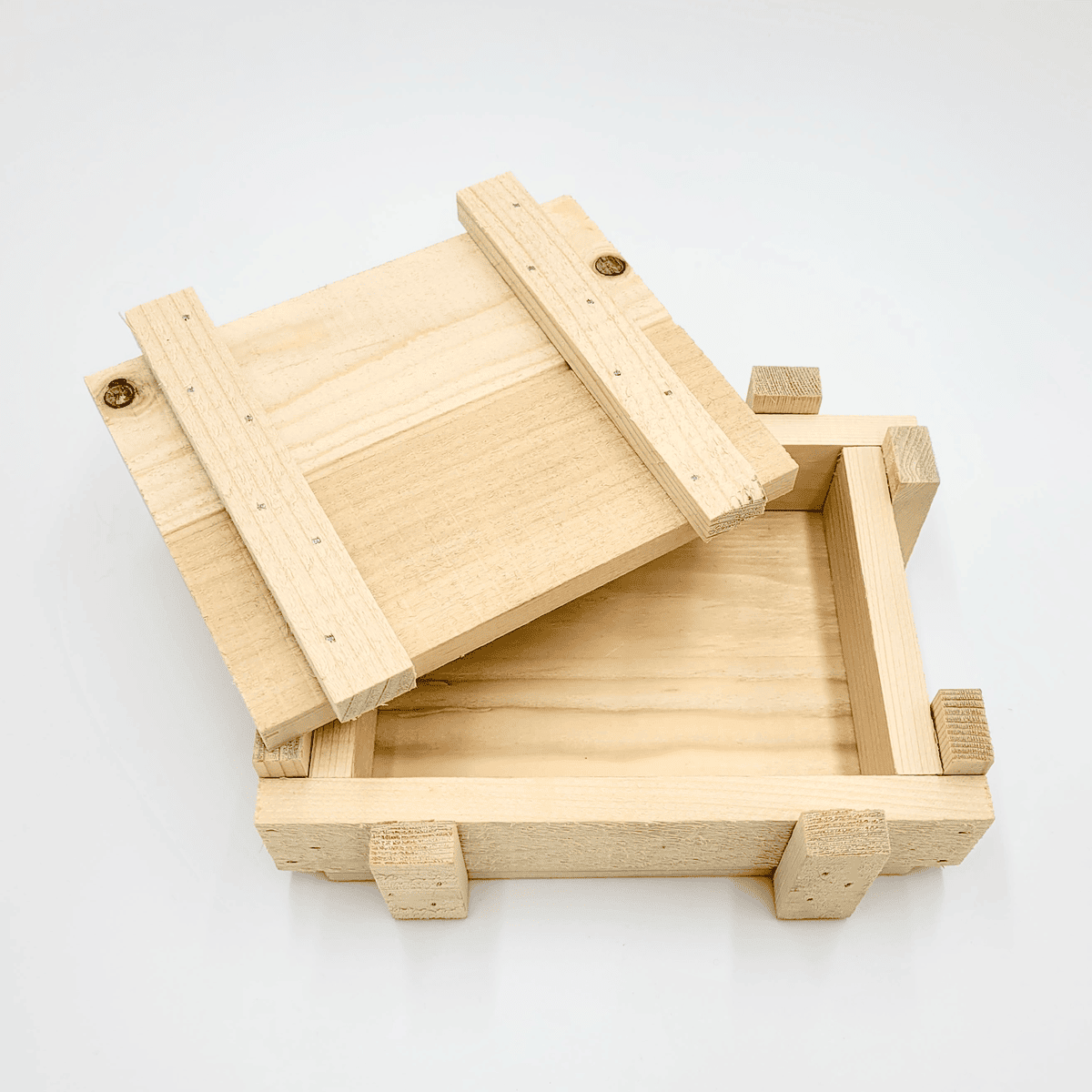 Die Holzkiste, eine Holzbox mit geöffnetem Schiebedeckel, gibt den Blick auf das Innere vor weißem Hintergrund frei.