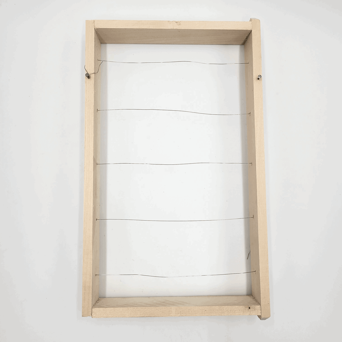 Der Honigrahmen besteht aus einem Holzrahmen mit fünf parallelen dünnen Drähten in der Mitte.