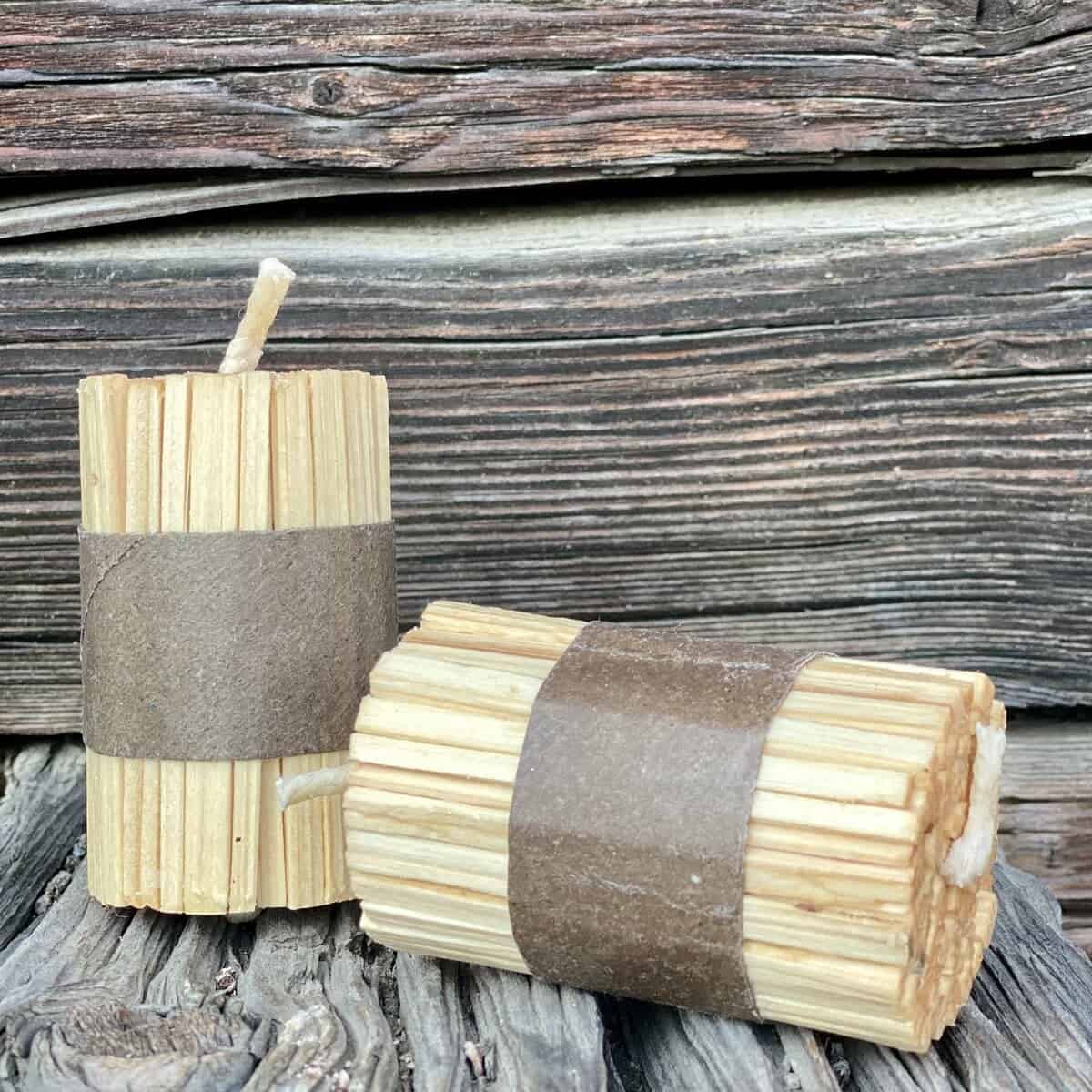 Zwei Bündel natürlicher K-LUMET-Feueranzünder, eingewickelt in braune Papierbänder, liegen auf einer rustikalen Holzoberfläche.