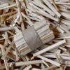 Ein mit Klebeband zusammengebundenes Bündel K-LUMET, umgeben von zusätzlichen losen Holzstäbchen.
