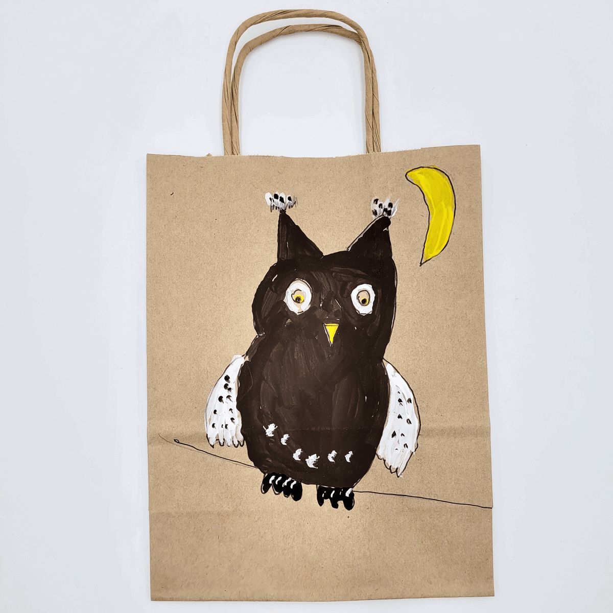 Bemalte Papiertasche mit einer handgemalten Eule und einem Halbmond auf braunem Papier.