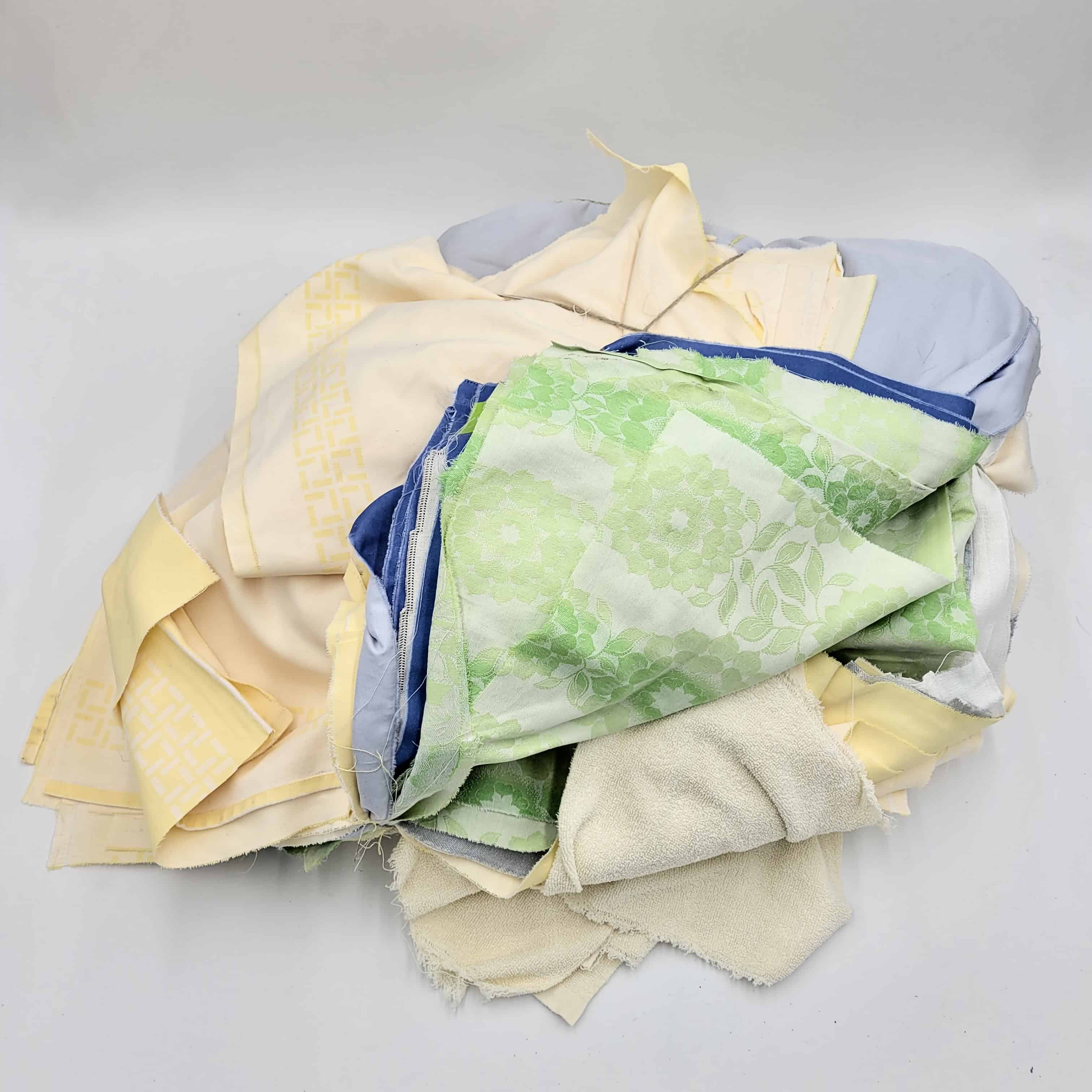 Eine Sammlung von Putzlappen-Stoffresten in Pastelltönen wie Grün, Blau und Gelb mit verschiedenen Mustern.