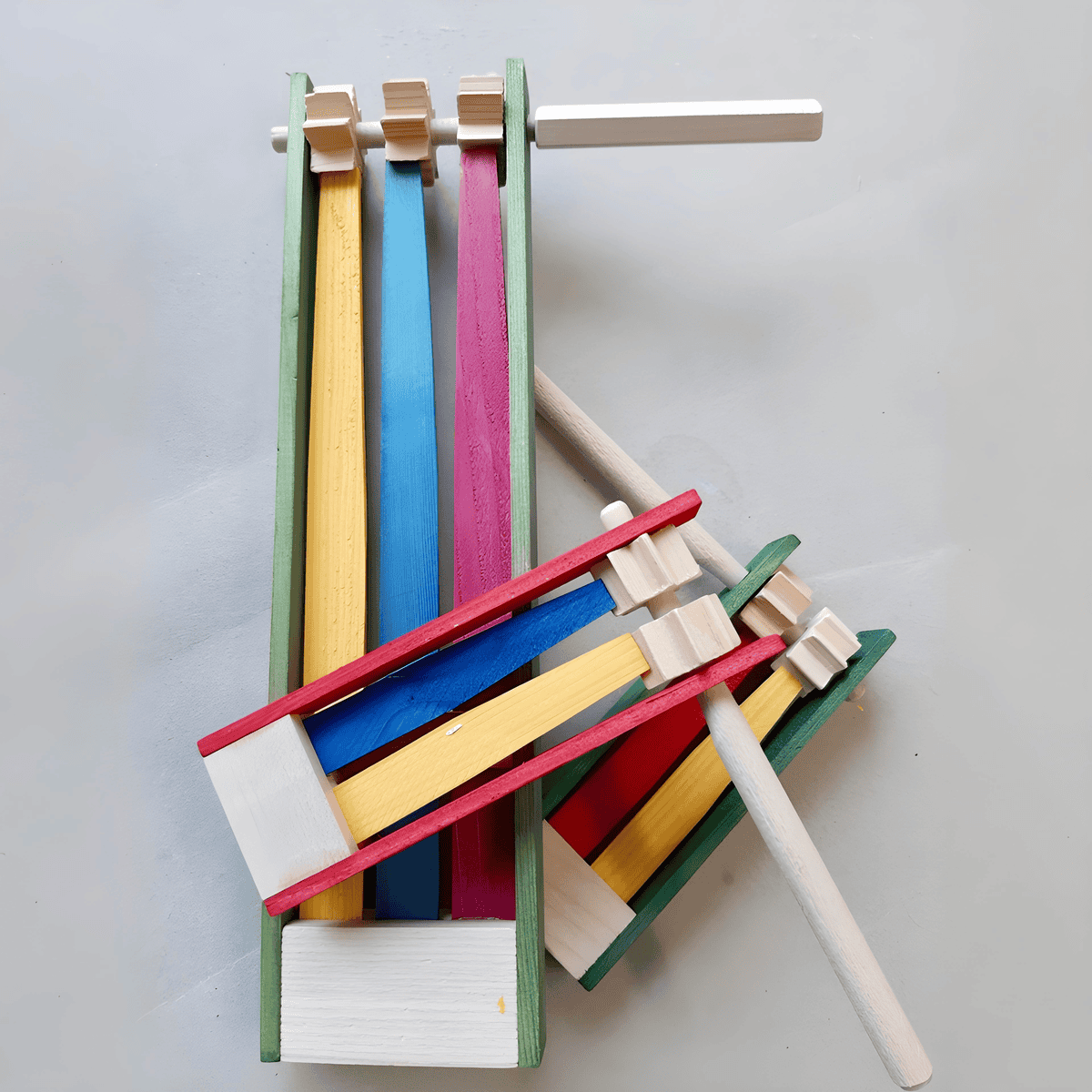 Rätsche aus Holzratschen in bunten Stapeln auf weißem Untergrund.