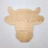 Das „Schneidebrett Kuh“ ist ein hölzernes Schneidebrett in Form eines Kuhkopfes auf grauem Untergrund.