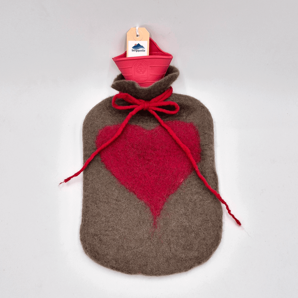 Eine Wärmflasche von Bettflasche mit Filzhülle im roten Design mit brauner Hülle, verziert mit einem großen roten Herz und einer Schleife am Hals.